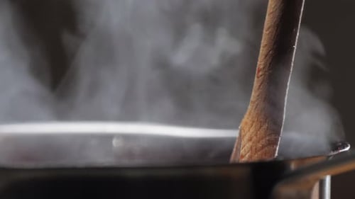 Wooden Spoon Stirring Steaming Water in Pot