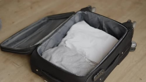 A Man Collects Things in an Open Suitcase Travel or Business Trip Folds and Packs Clothes in Luggage