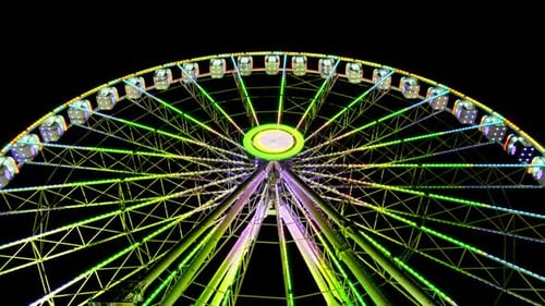 Großes, erstaunlich beleuchtetes, buntes, rotierendes Riesenrad im Hintergrund, dunkle Himmelsnacht. Kirmes.