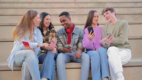 Smiling Teens Sitting on Steps Using Cell Phones
