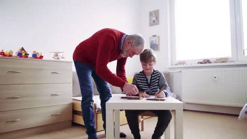 Älterer Großvater mit einem kleinen Enkel zu Hause beim Zeichnen