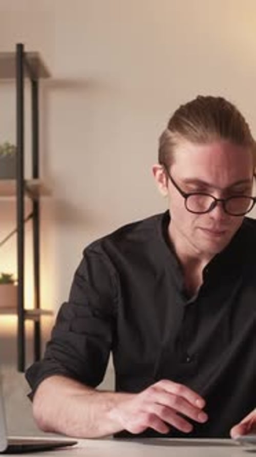 Man Working at Desk with Laptop and Phone