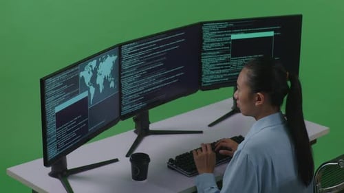 Side View Of Asian Woman Using Computer To Write Code With Multiple Screens In Green Screen