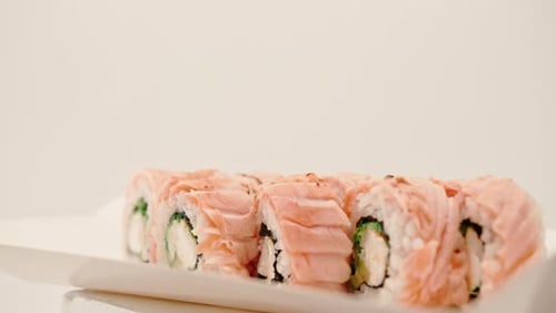 close-up of a roll with baked salmon, cucumber and cheese on a white background in a sushi delivery