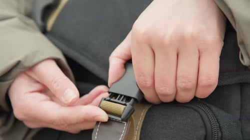 Gros plan de la personne qui attache son sac à dos en train d'ajuster la sangle de son équipement de plein air