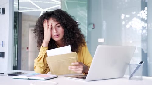 Worried Woman Opens Letter at Office Desk