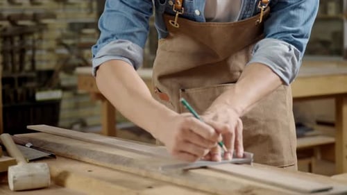 Carpenter Measuring Wood Plank in Workshop with Tools