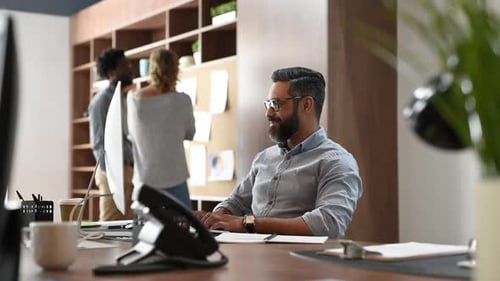 Glücklicher Geschäftsmann aus dem Nahen Osten, der sich in seinem Büro entspannt und dabei auf den Computerbildschirm schaut