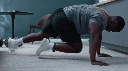 Focused African American Man Under House Arrest Doing Mountain Climbers Exercise