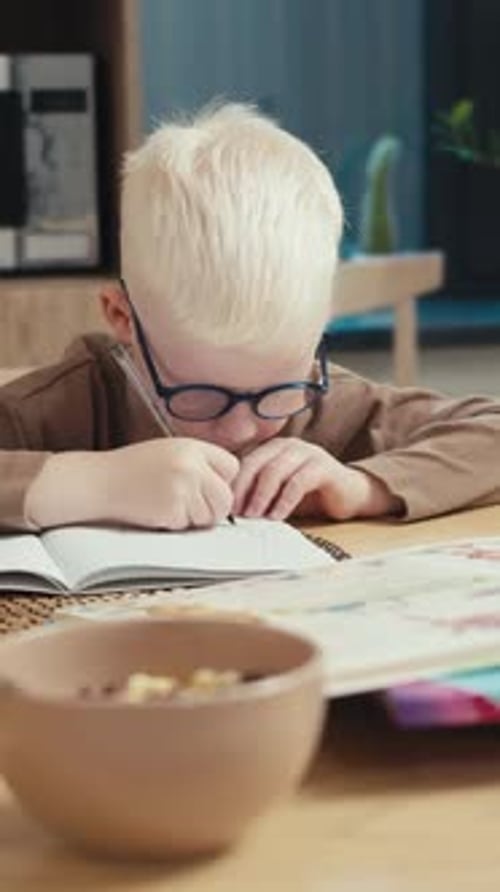 Child Writing in Notebook at Table Indoors