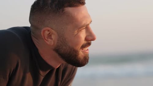 Surfista cansado recupera o fôlego depois de surfar contemplando o próximo passeio ao pôr do sol