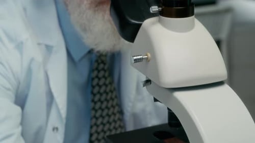 Senior Scientist Looking Through Microscope in Lab