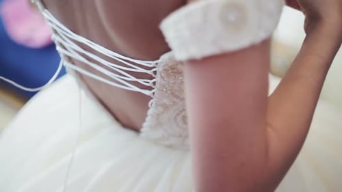 Brautjungfer bindet Schleife am Hochzeitskleid