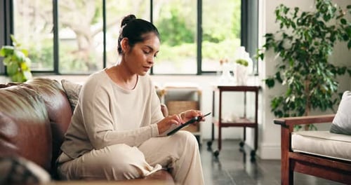 Woman Using Tablet on Sofa in Sunny Living Room