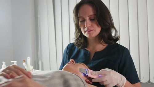 Practitioner Massages Customer Face with Ultrasound Tool in Bright Spa Room