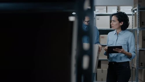 Female Inventory Manager Shows Digital Tablet Information to a Worker Holding Cardboard Box, They T