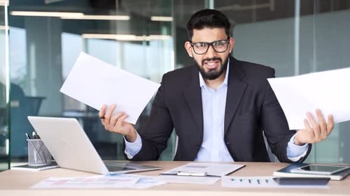 Businessman in Suit Frustrated with Documents at Desk