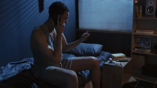 Young Man Talking on Phone in Bedroom at Night