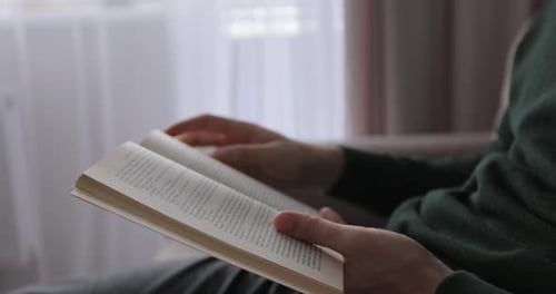 Junger Mann liest ein Buch und blättert Seiten um