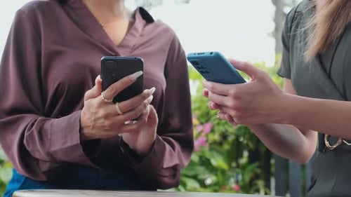 Women Using Phones Together Outdoors in Urban Setting