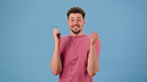Young Adult Cheers While Looking at Mobile Phone