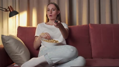 Woman Eats Popcorn and Watches Television at Home