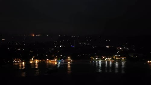 Nighttime Aerial Hyperlapse Footage of Lively Beachfront Coastal City Lights Reflect on Ocean Waves