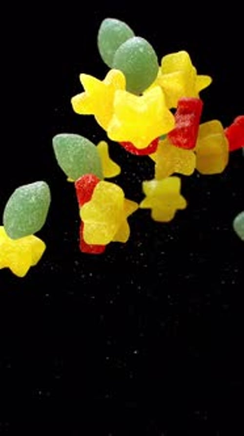 Colorful gummy candies floating against black background