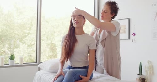 Professional female chiropractor adjusting her patient's spine and back while she sits on a bed