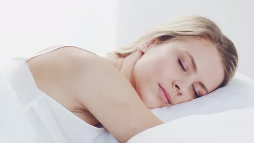 Woman sleeping in bed awakes looks at camera
