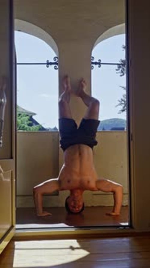 Man Doing Handstand on Balcony