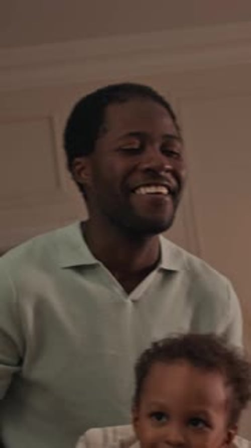 Father Lifting Child in Air with Joy Indoors