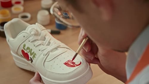 Caucasian Man Drawing on White Sneakers in Studio
