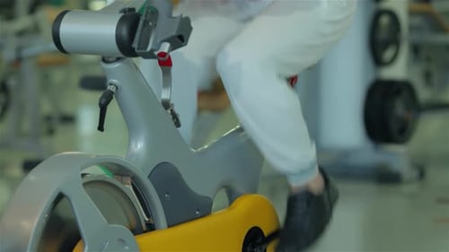 Man Works Out on Exercise Bike at Gym