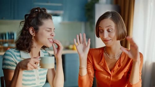Süße beste Freunde teilen Geheimnisse, wenn sie zusammen in der Küche sitzen, Nahaufnahme, lächelnde Frauen