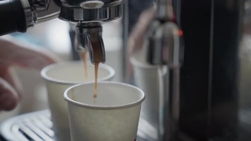 creamy espresso streams pouring into paper cups at busy coffee station