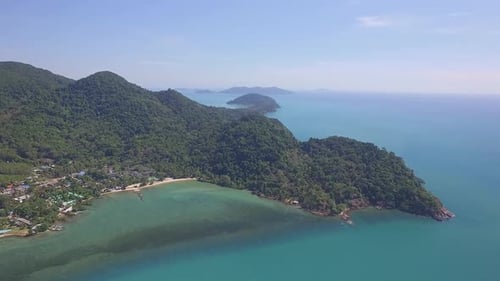 Aerial drone shot of tropical island with mountains covered in jungle , a beach and ocean