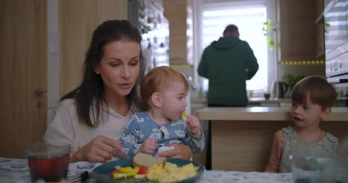 Mother and Children Eating Breakfast Together at Home