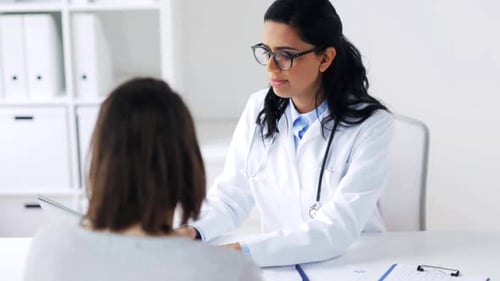 Smiling doctor shows medical data on laptop to indian woman patient at hospital
