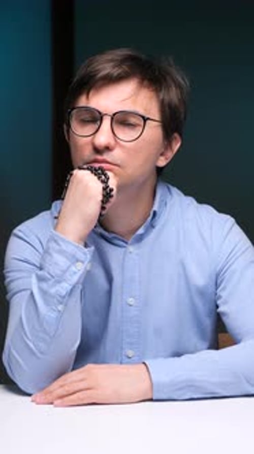 Man in Glasses Sits Contemplatively Indoors