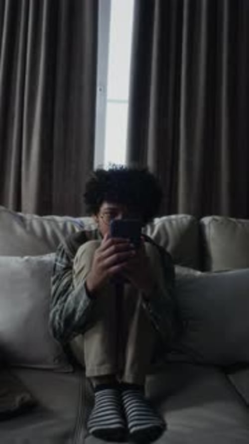 Anxious Black Boy Checking Social Media for Messages then Staring at Window