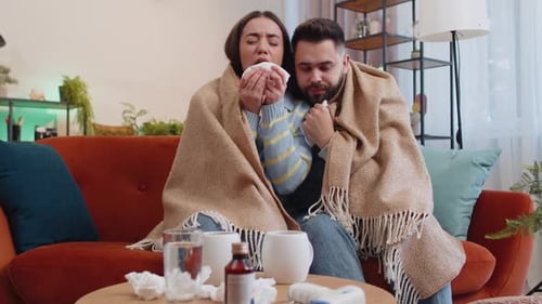 Un homme de famille malade et malade souffrant du froid, assis sur le canapé de la maison, éternue avec de la morve