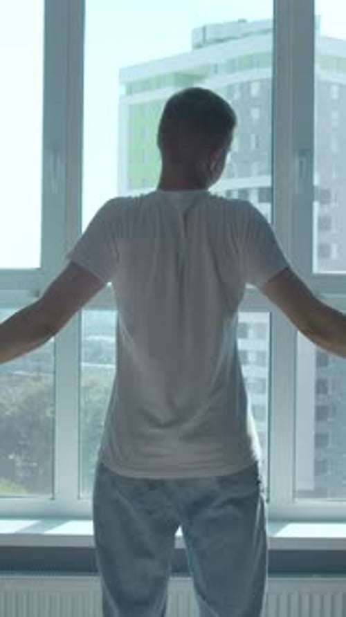 Early Morning a Man at the Window Raising His Hands and Stretching Media Looking at the City