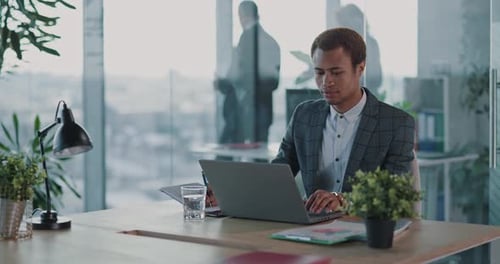 Focused Man Working on Laptop in Bright Office