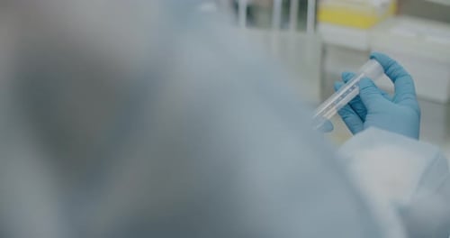 Gloved Hand Holding Lab Tube in Medical Setting