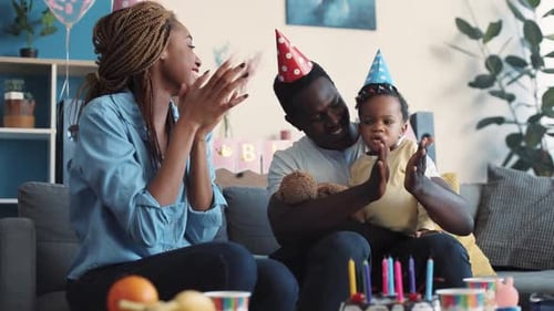 Family celebrates infant's birthday with cake and clapping