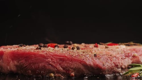 Fresh Marbled Beef with Pepper Salt and Rosemary Closeup Macro Cooking Juicy Steak on Grill with Oil