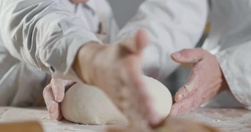 Close up of a baker kneading with his hands to prepare the bread to put in the oven. Concept of: a
