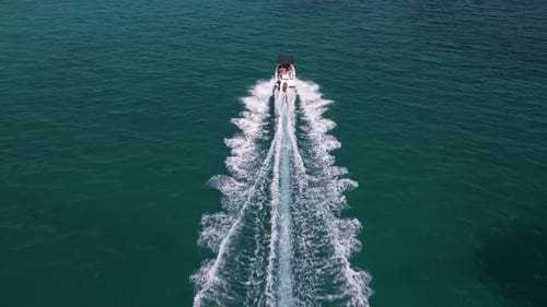 Aerial View of a Speedboat Moving Through Teal Sea Water Leaving a Dramatic Wake Trail Behind