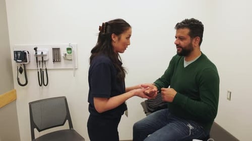 Physiotherapeut untersucht das Handgelenk eines Patienten im Untersuchungsraum der Klinik 30-34 Jahre